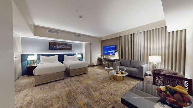 Una habitación de hotel con cama, sofá, televisor y mesa de centro.