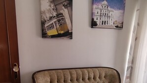 Una stanza con un divano trapuntato, una porta e due quadri alle pareti.