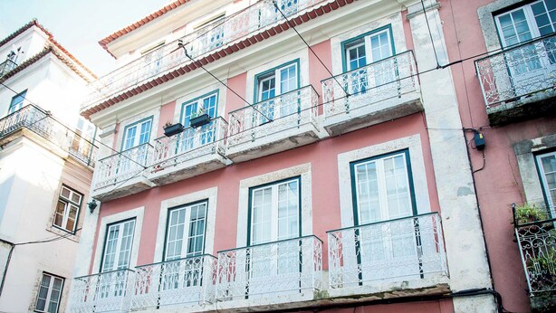 Un edificio a più piani con balconi, un negozio al piano terra e una strada acciottolata.
