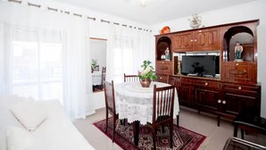 Zona pranzo con tavolo, sedie, televisore e pensili in legno.