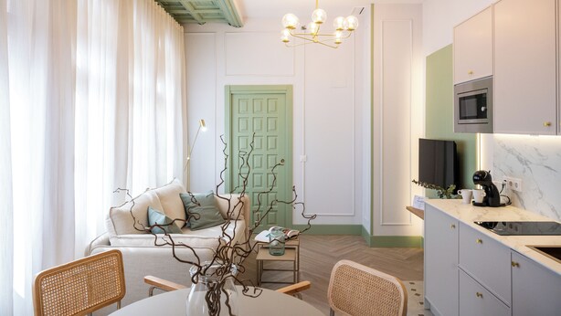 A modern kitchen with a built-in microwave, a dining area with a round table and chairs, and a green door in the background. - 4Duques Apartments (Cáceres)