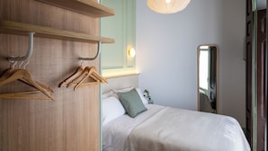 A bedroom with a bed, wooden wardrobe, and a mirror. - 4Duques Apartments (Cáceres)