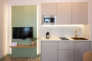 Eine moderne Küche mit integriertem Mikrowellenherd, Spüle und einem flachbildfernseher an der Wand.