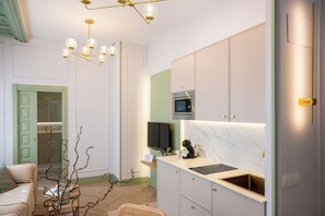 Eine moderne Küche mit Einbauofen, Kaffeemaschine und Fernseher über der Arbeitsfläche.
