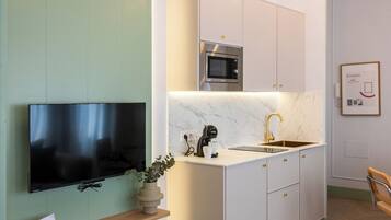 Una cocina moderna con televisor integrado, electrodomésticos de acero inoxidable y encimera de mármol.