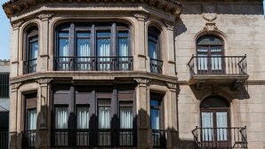 A corner building with bay windows, a balcony, and a small window with a decorative element. - 4Duques Apartments (Cáceres)