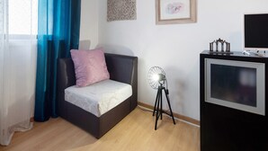 Ein Schlafzimmer mit einem Bett, einem Standventilator, einem Fernseher und einer Wanddekoration.