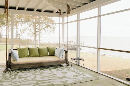 A room with a wooden bench, a small table, and a view of the outdoors.