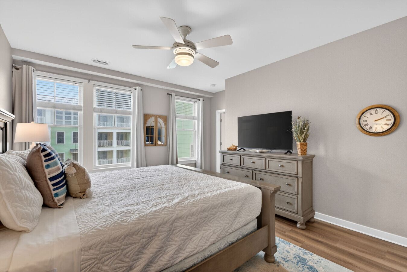 A bedroom with a bed, dresser, TV, and a ceiling fan.