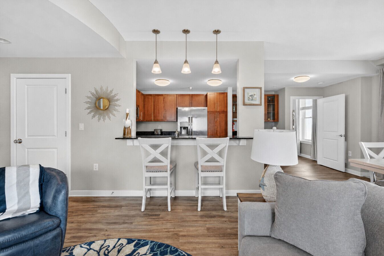 A modern kitchen with wooden cabinets, a stainless steel refrigerator, and pendant lighting.