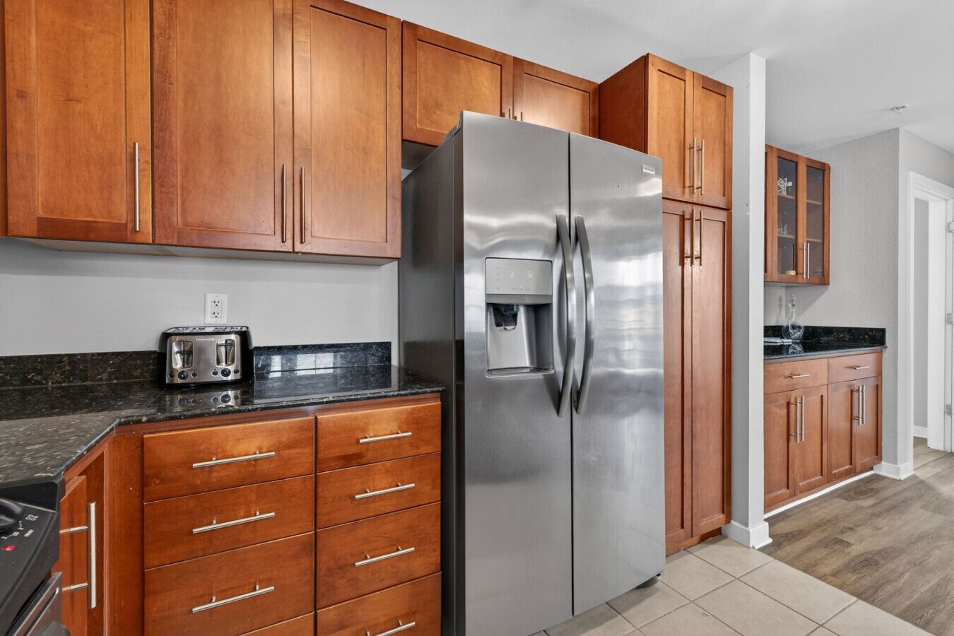 A kitchen with wooden cabinets, a stainless steel refrigerator, a built-in water dispenser, and a toaster.