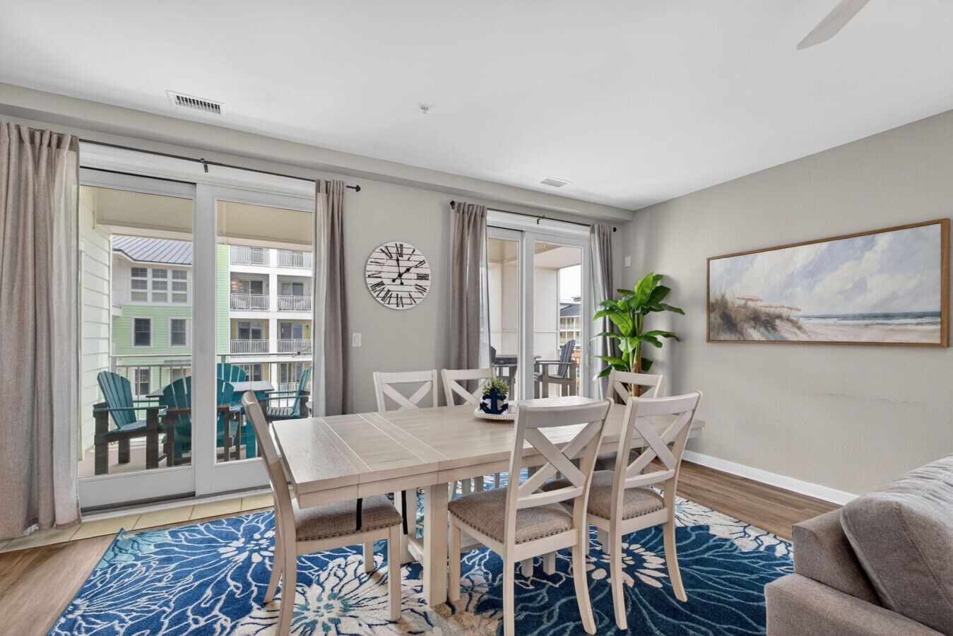 Un coin repas avec une table et des chaises, une horloge au mur et une vue à travers les portes vitrées.