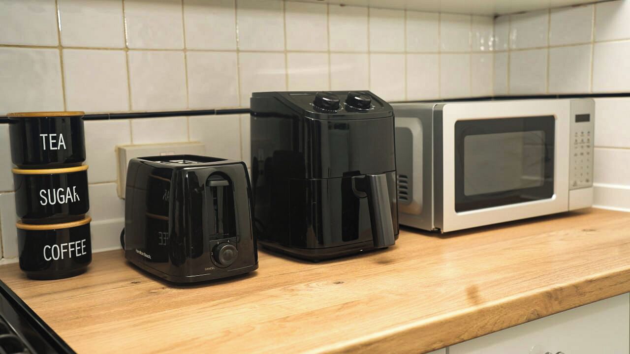 Un comptoir de cuisine avec une machine à café, un distributeur de thé et un four à micro-ondes.