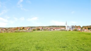 Ett lantligt landskap med en kyrka, hus och öppna fält.
