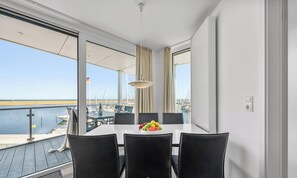 Een balkon met een tafel en stoelen, uitzicht op zee, en een vlag.