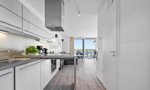 Een moderne keuken met een centraal eiland, een eethoek en uitzicht op zee.