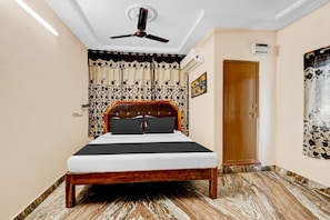 Ein Schlafzimmer mit einem Bett, einem Deckenventilator, einer Klimaanlage, einer Tür und einem Vorhang.
