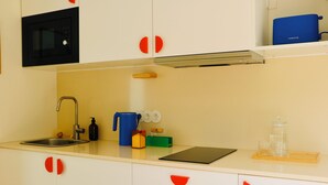 A kitchen with a sink, faucet, microwave, and various kitchen items on the counter. - Araça Studio - Atlantic Mountain Living Surrounded by mountains and nature (São Vicente)