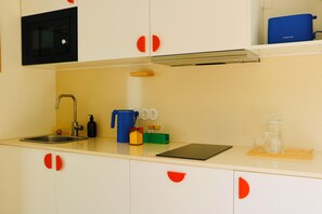 A kitchen with a sink, faucet, microwave, and various kitchen items on the counter. - Araça Studio - Atlantic Mountain Living Surrounded by mountains and nature (São Vicente)