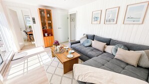 A living room with a grey sofa, wooden coffee table, and framed pictures on the wall.