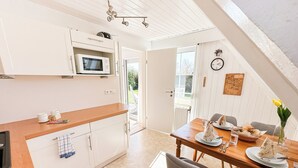 A kitchen with white cabinets, a microwave, and a dining area with a table set for two.