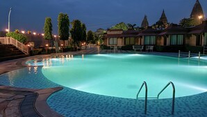 A swimming pool with a tiled deck, surrounded by buildings and trees. - Orchha Resort- by the river (Nivari)