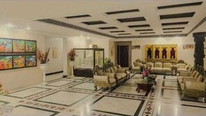 A spacious lobby with a high ceiling, patterned floor, and a seating area with sofas and armchairs. - Orchha Resort- by the river (Nivari)