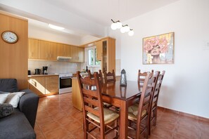 Una cucina moderna con mobili in legno, un tavolo da pranzo con sedie, un orologio e un quadro appeso al muro.