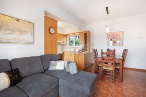 Una cucina moderna con mobili in legno, un'area pranzo con tavolo e sedie, e un divano grigio con cuscini.