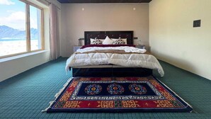 A hotel room with a bed, a window with a view, and a patterned rug.