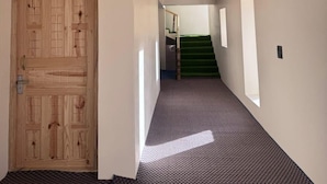 A hallway with a wooden door, a carpeted floor, and a staircase in the distance.