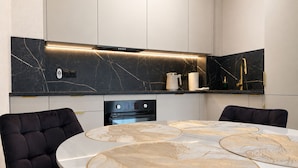 Une cuisine moderne dotée d’un îlot central, d’appareils électroménagers intégrés et d’un élégant revêtement mural.
