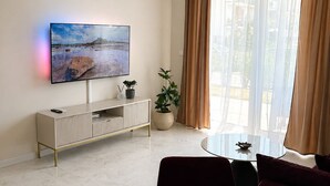 Un salon moderne avec un téléviseur à écran plat, une table de salle à manger ronde et un canapé.