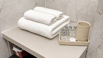 A bathroom with a towel rack, a cup, and a soap dispenser on a shelf.