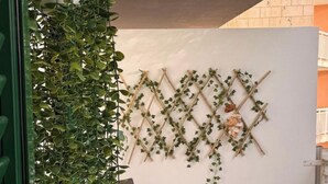 A room with a white wall, a wooden trellis with climbing plants, and a window with a view of a brick building. - Comfy 2-bedroom apartment with AC in Santa Maria (Santa Maria)