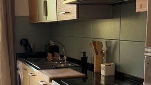 A modern kitchen with a stainless steel sink, wooden cabinets, and a built-in range hood. - Comfy 2-bedroom apartment with AC in Santa Maria (Santa Maria)