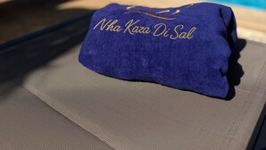 A blue towel with embroidered text on a lounge chair by a pool, with a building in the background. - Comfy 2-bedroom apartment with AC in Santa Maria (Santa Maria)