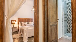 A bedroom with a bed, bedside table, lamp, and a view of a shower area. - Da Donata - A Private Retreat Stay (Pertosa)