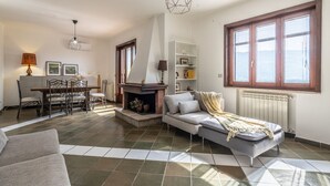 Ein Wohnzimmer mit Kamin, Sofa, Esstisch und Stühlen.