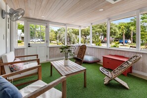 Una habitación con techo de madera, una puerta blanca, una mesa de madera, una silla, un armario rojo y vistas al exterior.