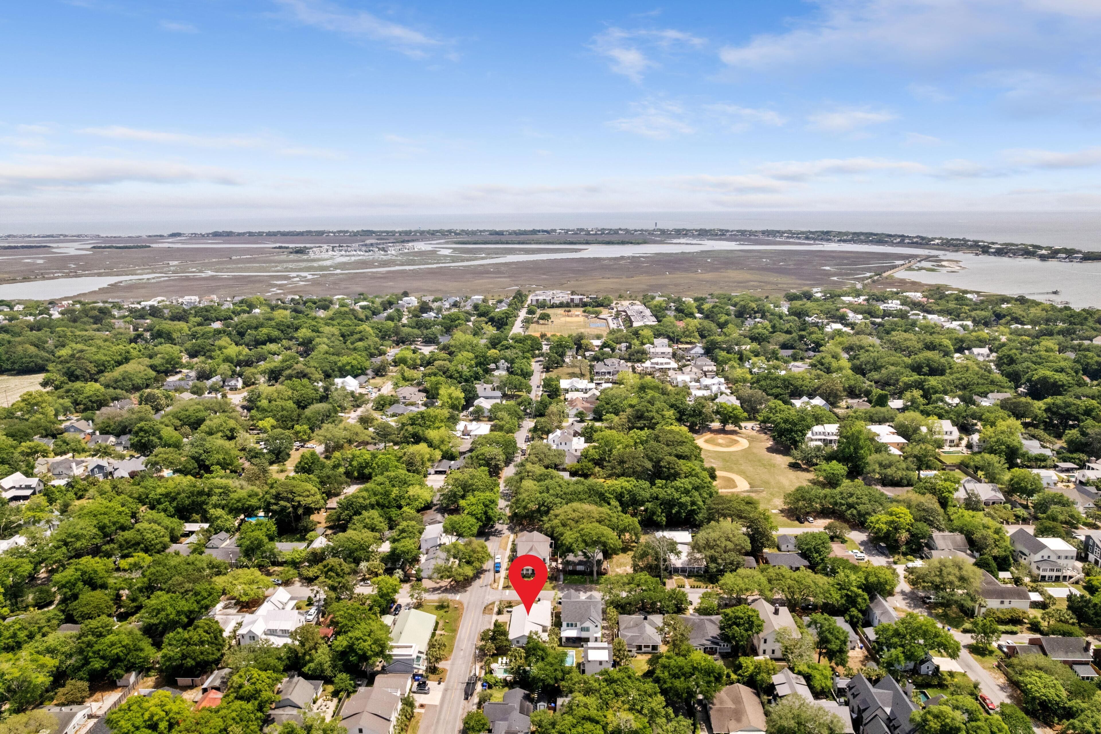 Luchtbeeld van een woongebied met huizen, bomen en een groot waterlichaam op de achtergrond.