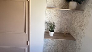 Una puerta con diseño de panel, una pared con estampado de papel tapiz floral y un estante con una planta en maceta y una guirnalda.