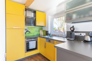 A modern kitchen with yellow cabinets, a built-in oven, a dishwasher, and a coffee maker. - Panoramic Mountain Views, Spacious Sauna, Dogs Welcome, Alpenjuwel 2 Oberstdorf (Oberstdorf)