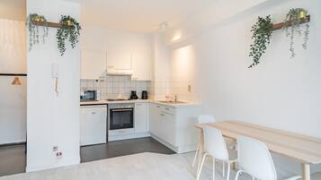 Een moderne keuken met witte kastjes, een houten eettafel en hangende planten.