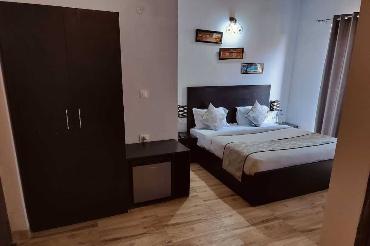 A bedroom with a bed, a wardrobe, a bedside table, and a wall-mounted light fixture.
