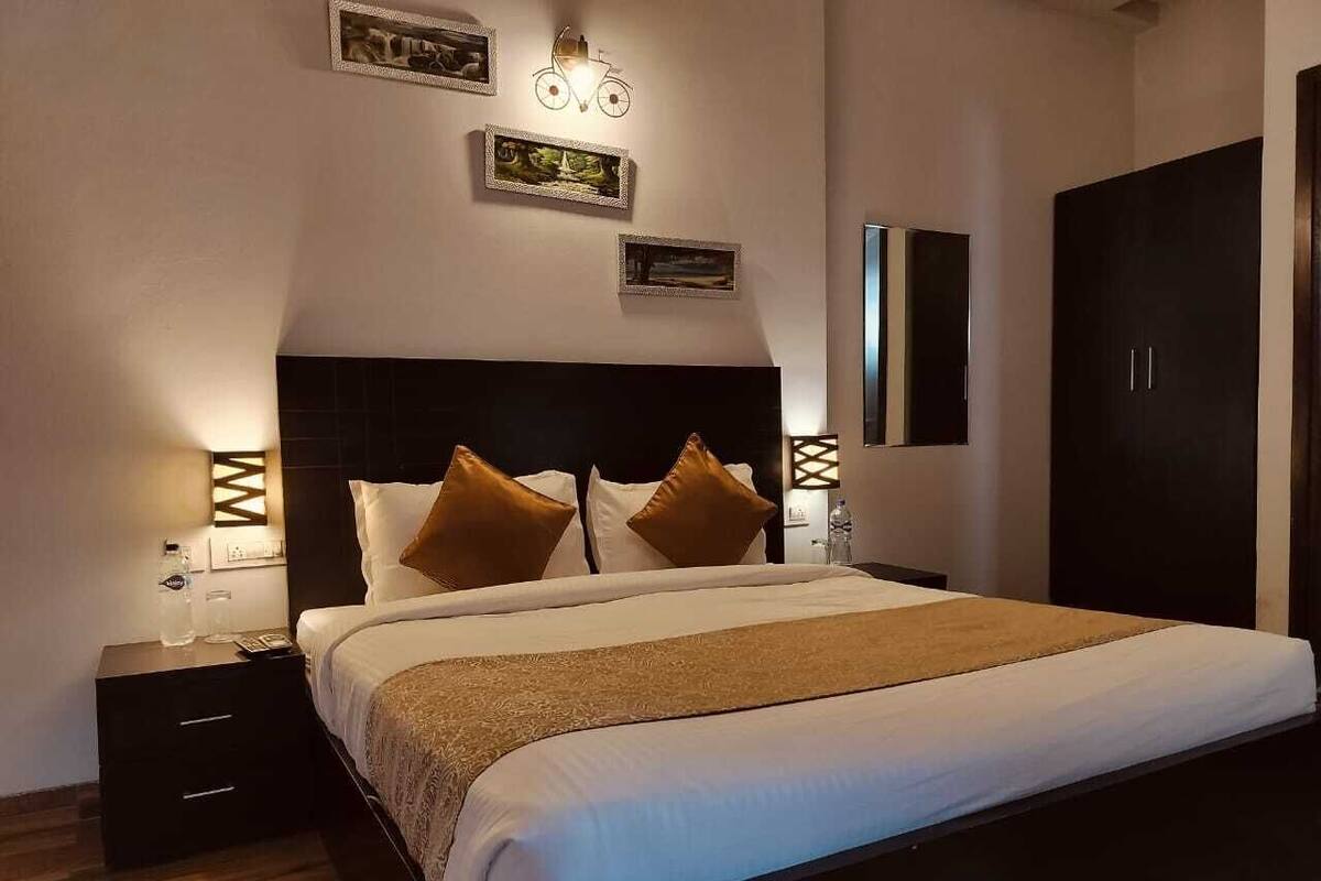 A neatly made bed with a headboard, a bedside table with a lamp, and wall-mounted artwork.
