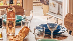Ein Esstisch, gedeckt mit Tellern, Gläsern, einer Flasche und einem Baguette.