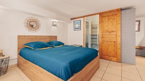 Ein Schlafzimmer mit einem Holzbett, einem kleinen Nachttisch, einer Wanduhr und einer Schiebetür.