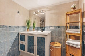 Ein Badezimmer mit Waschbecken, Spiegel, Handtuchhalter und Mülleimer.