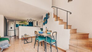Eine moderne Küche mit Essbereich, einer Treppe und einem sichtbaren Wohnzimmer.